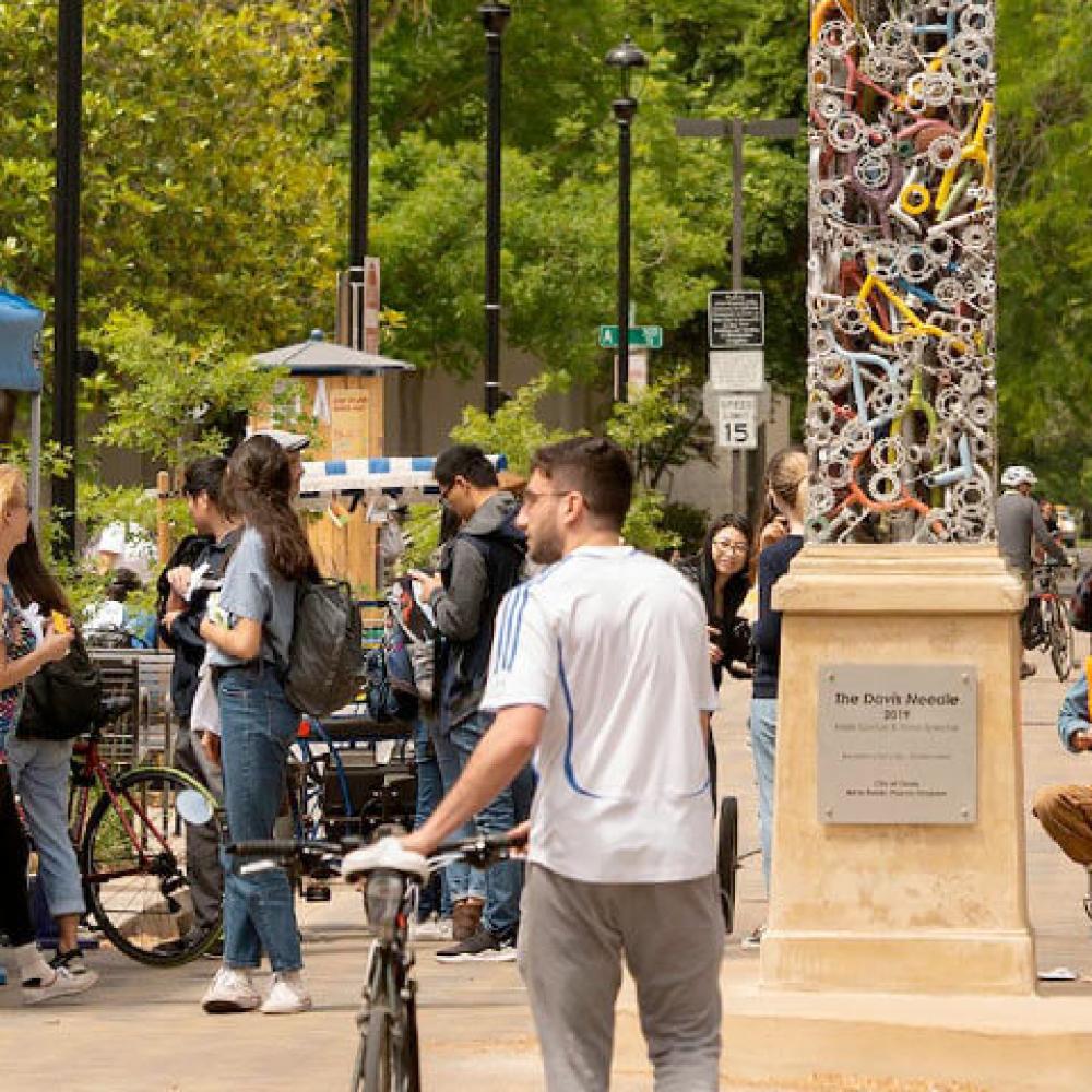 Student walking his bike through downtown Davis