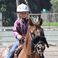 "little girl riding a horse and smiling"