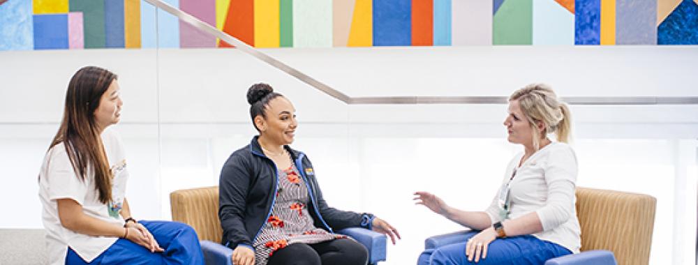 three women talking with one another at uc davis nursing school