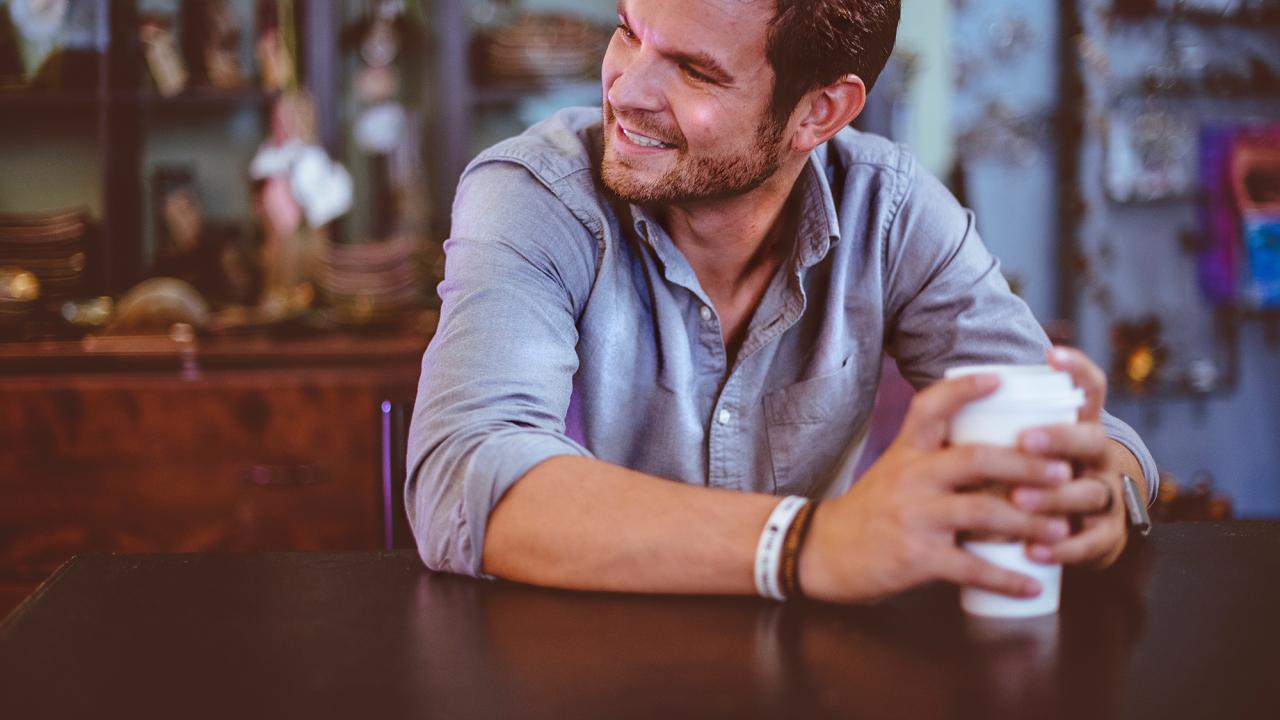 man smiling while holding a cup of coffee